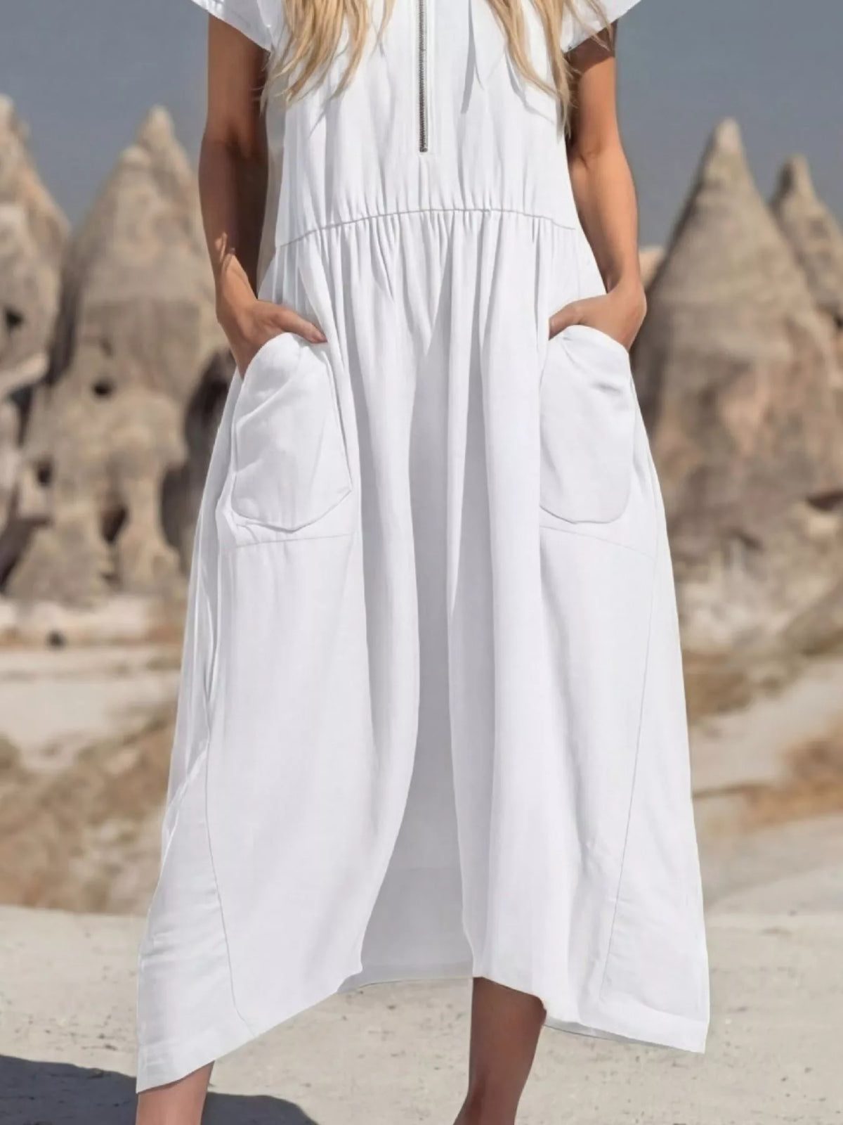 Person wearing a white dress with a scenic background of rock formations.