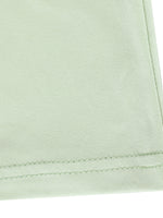 Close-up of light green fabric with a visible seam on a white background