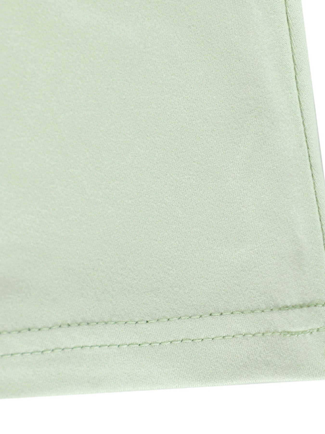 Close-up of light green fabric with a visible seam on a white background