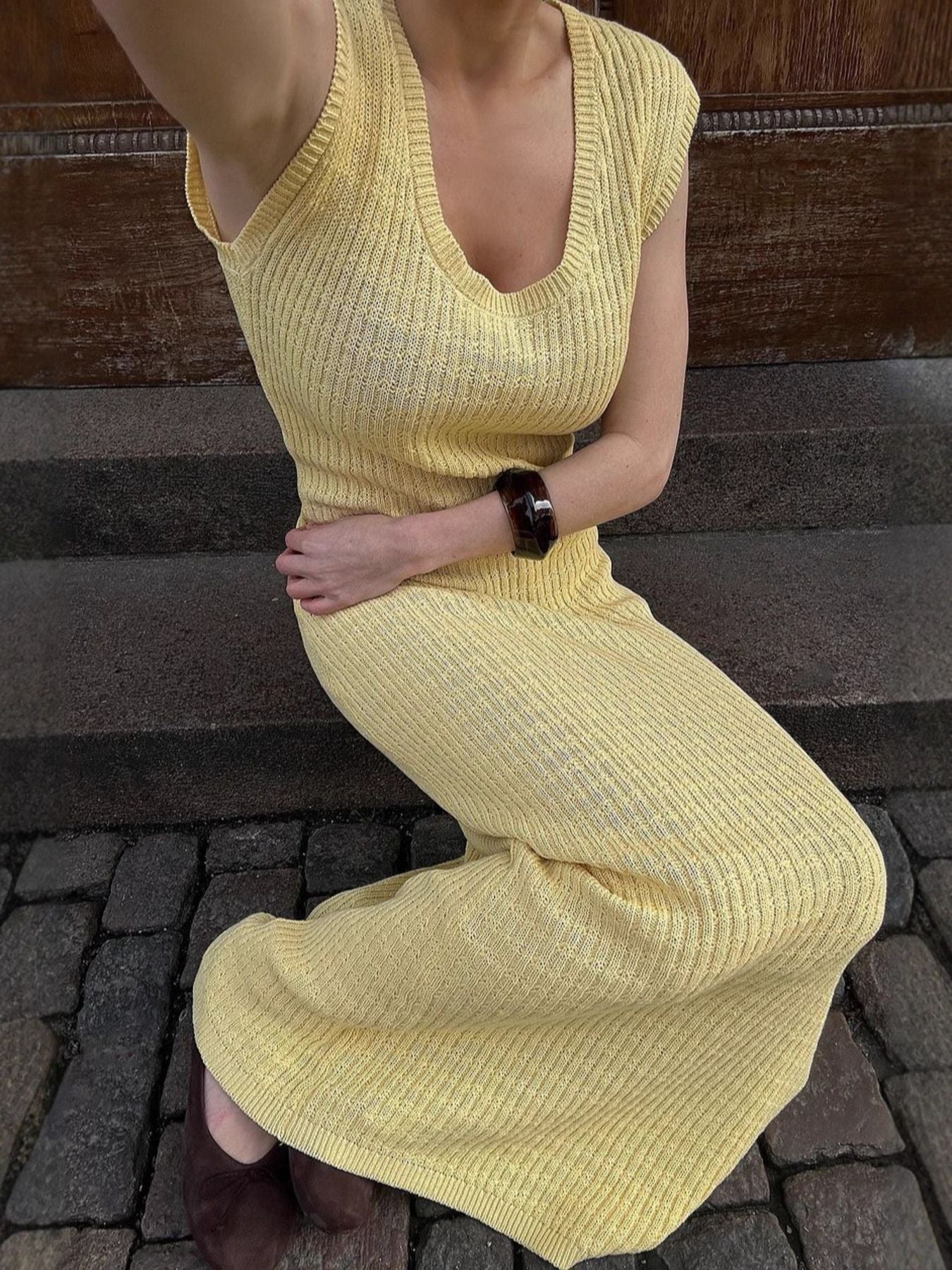 Person wearing a yellow ribbed dress sitting on steps.