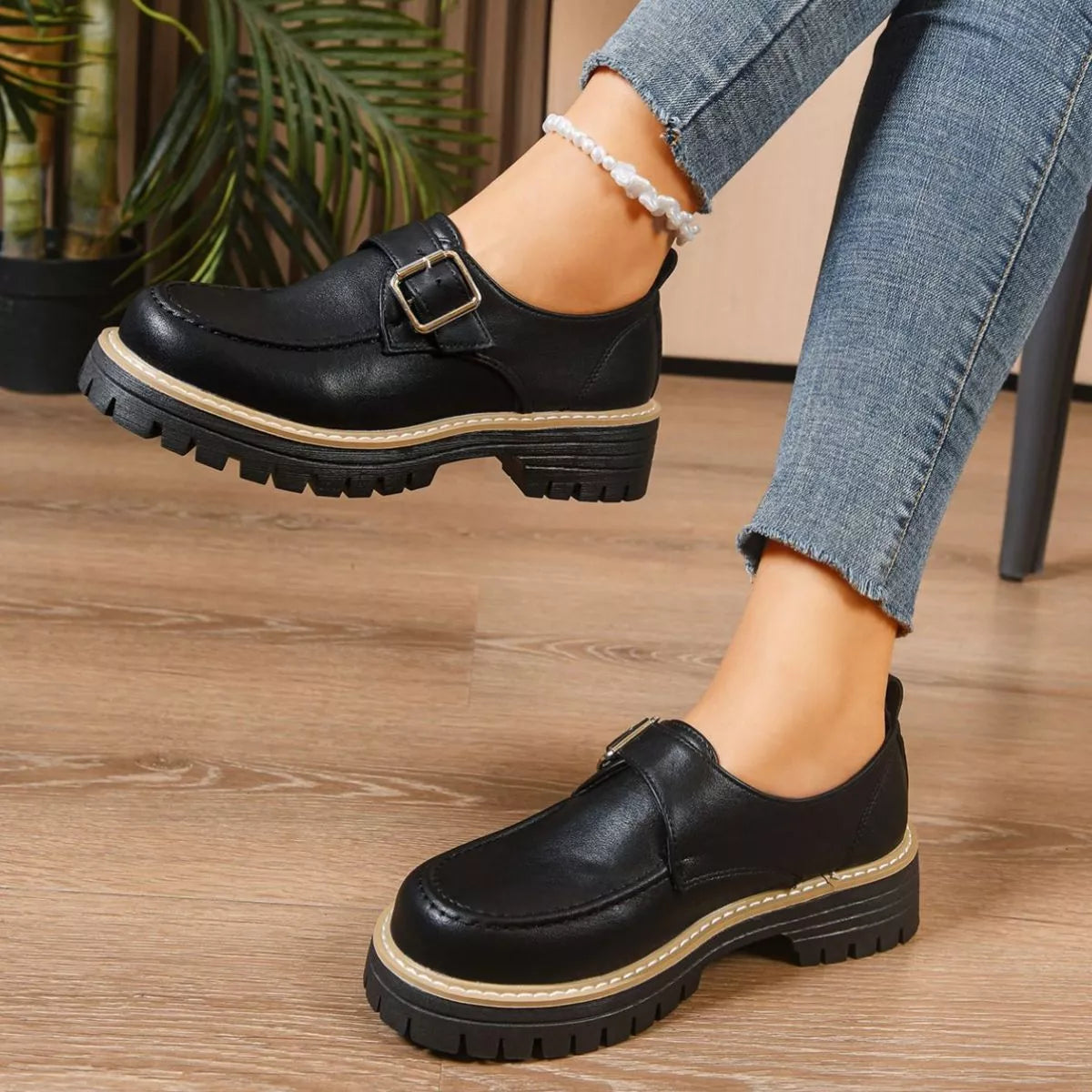 Black leather shoes with a buckle on a wooden floor