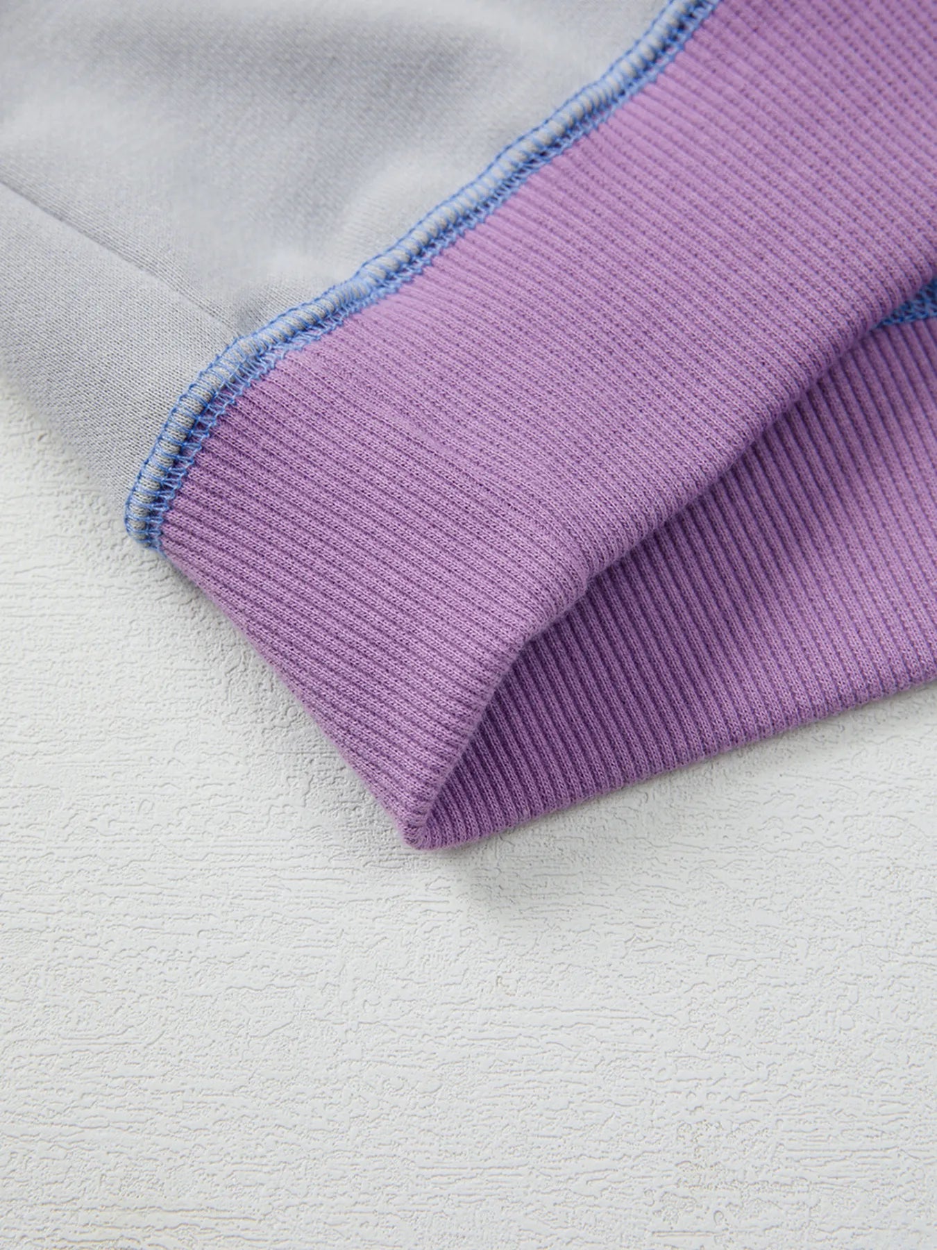 Close-up of a purple fabric edge on a light gray background