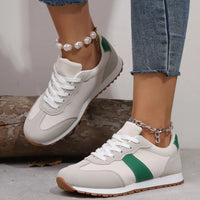 White sneakers with green accents worn by a person on a neutral background