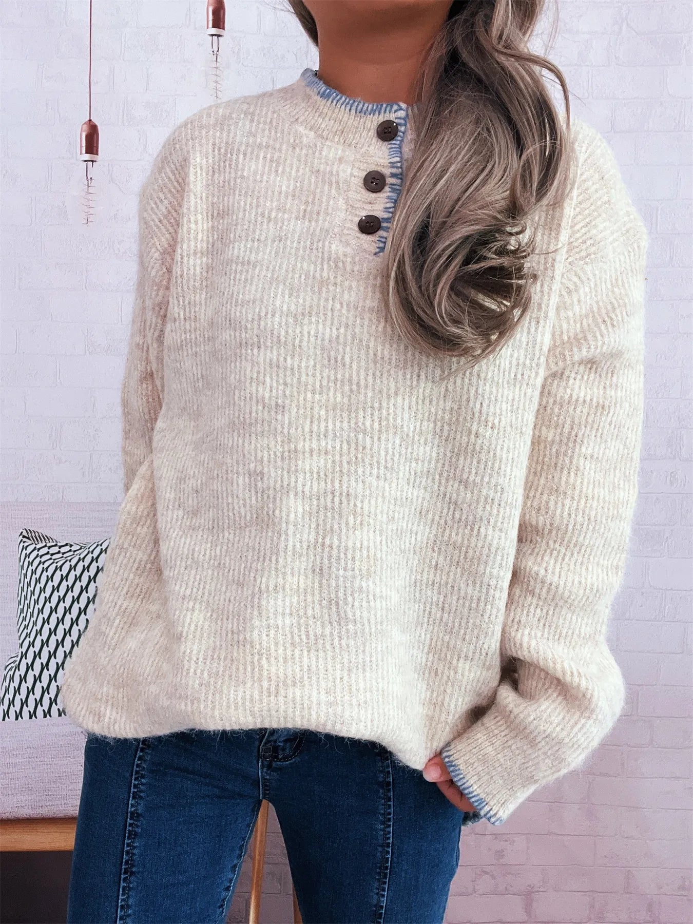 Person wearing a beige sweater with button details against a light background