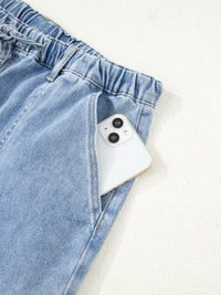 White phone in a blue denim pocket on a light gray background