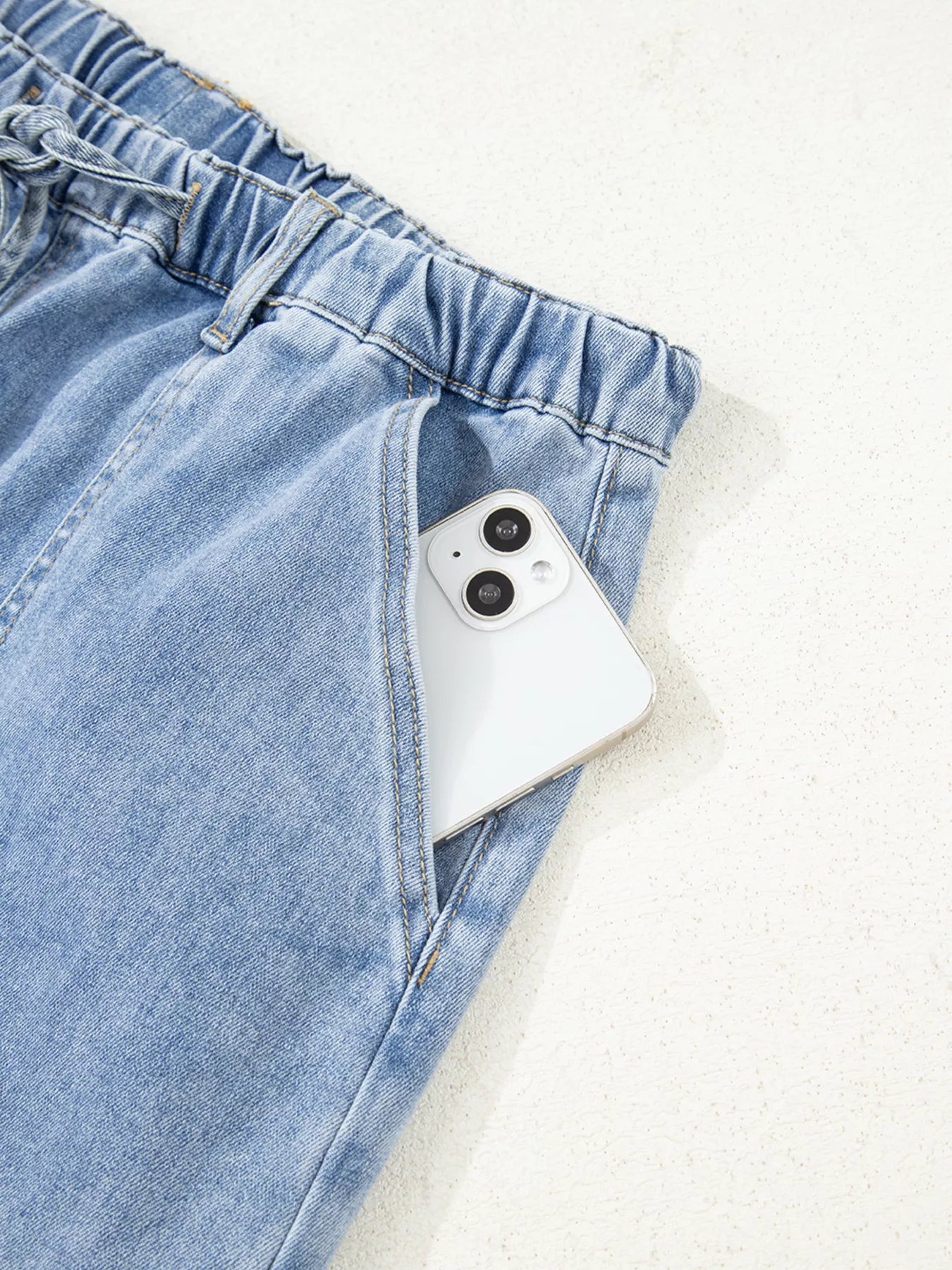 White phone in a blue denim pocket on a light gray background