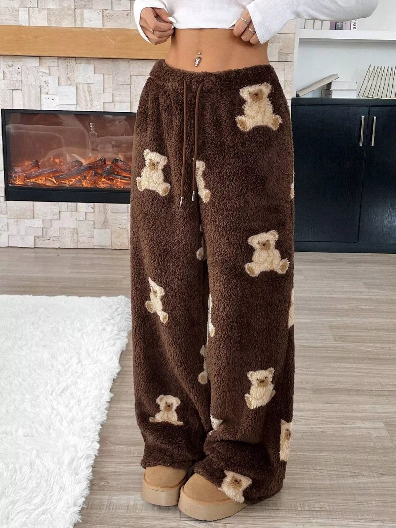 Brown fleece pants with teddy bear pattern worn by a person in a home setting.