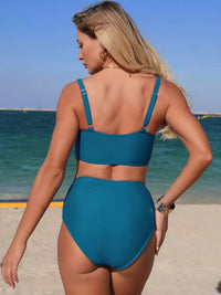 Woman wearing a blue bikini on a beach with ocean in the background