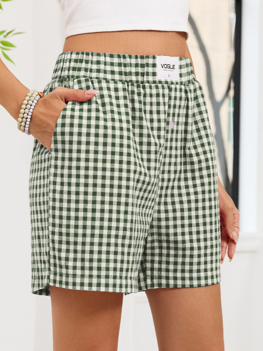 Green and white checkered shorts worn by a person with a blurred background