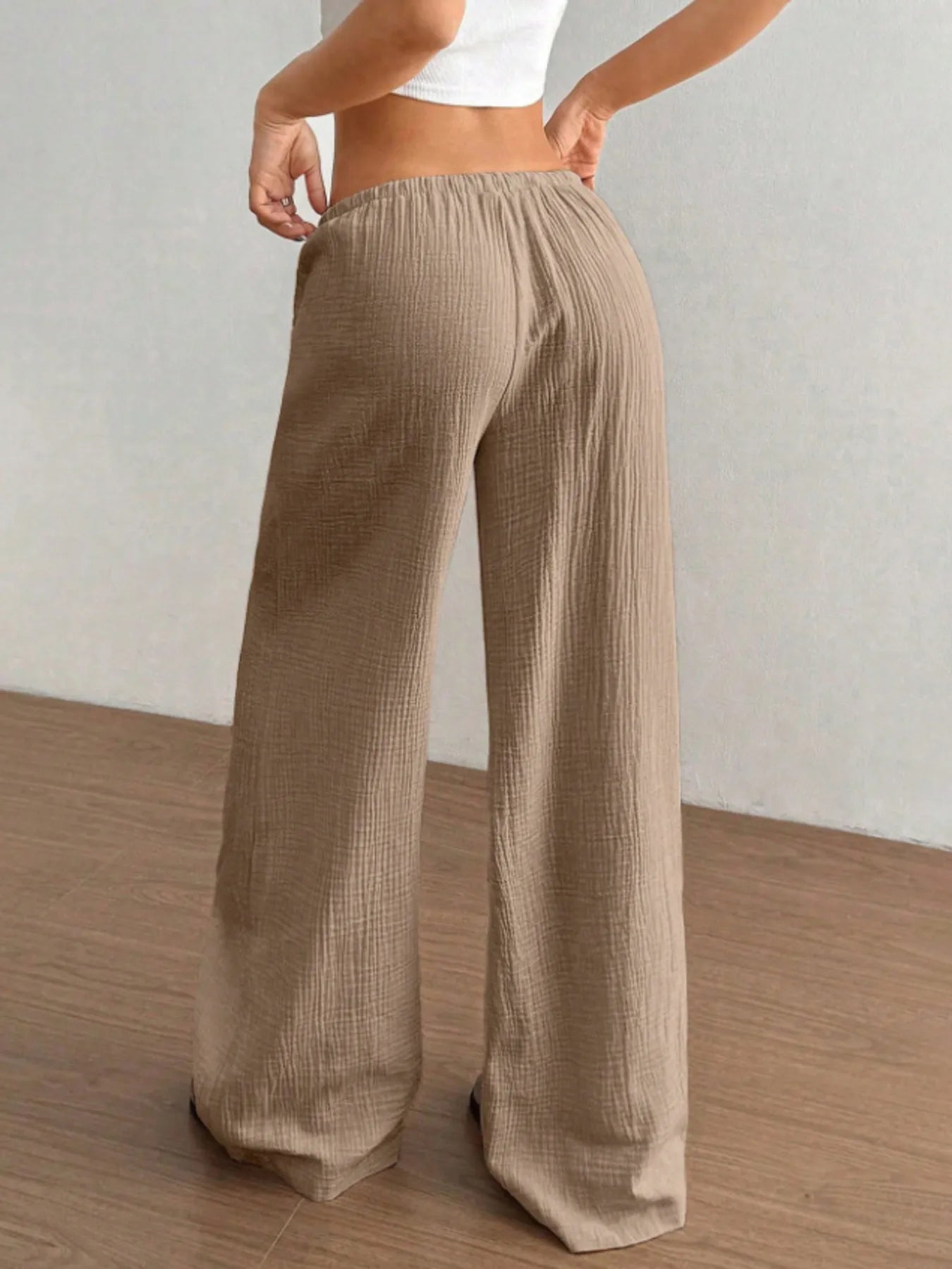 Beige wide-leg pants worn by a person on a wooden floor with a neutral background