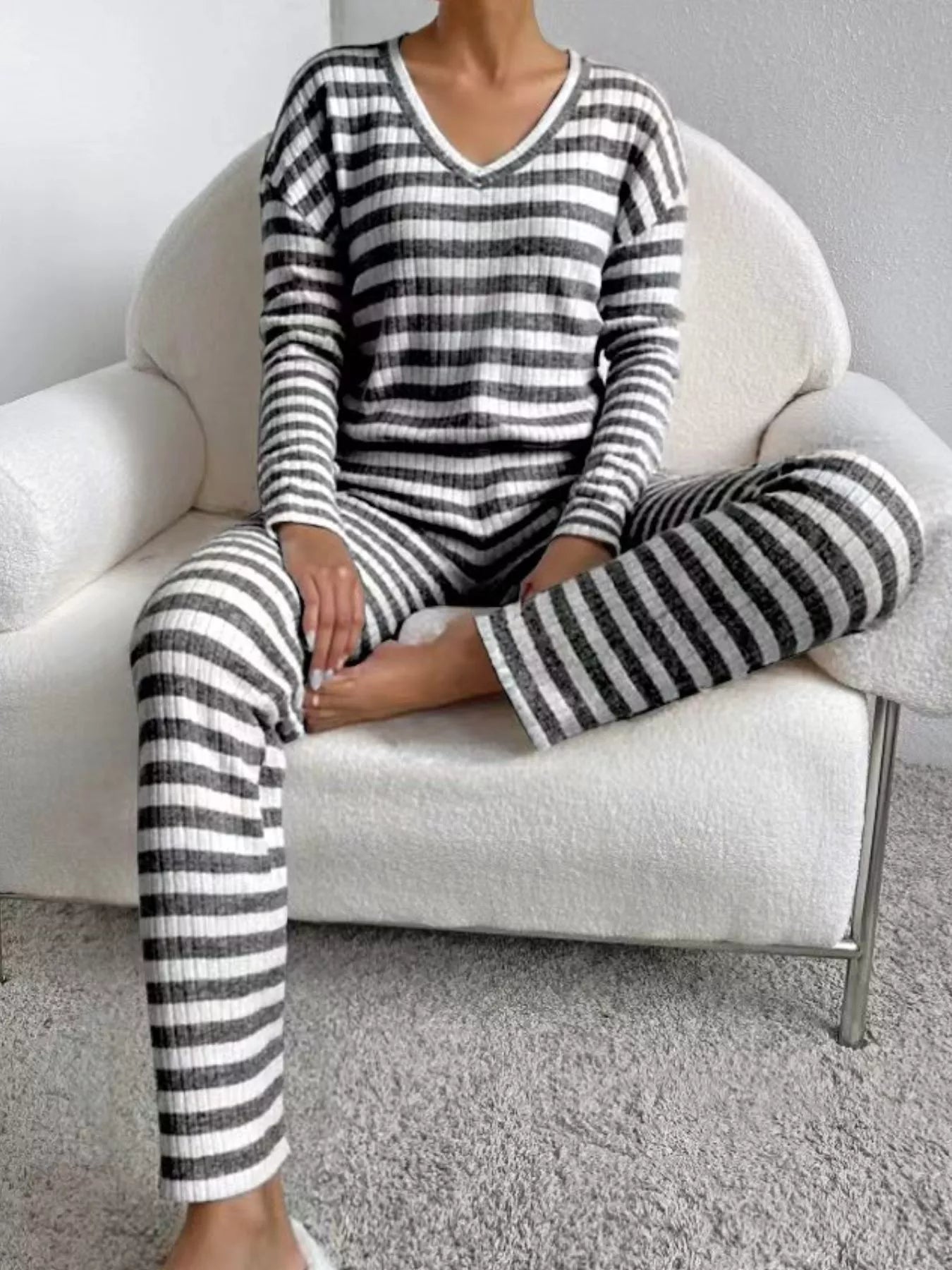 Person wearing black and white striped pajamas sitting on a white chair.