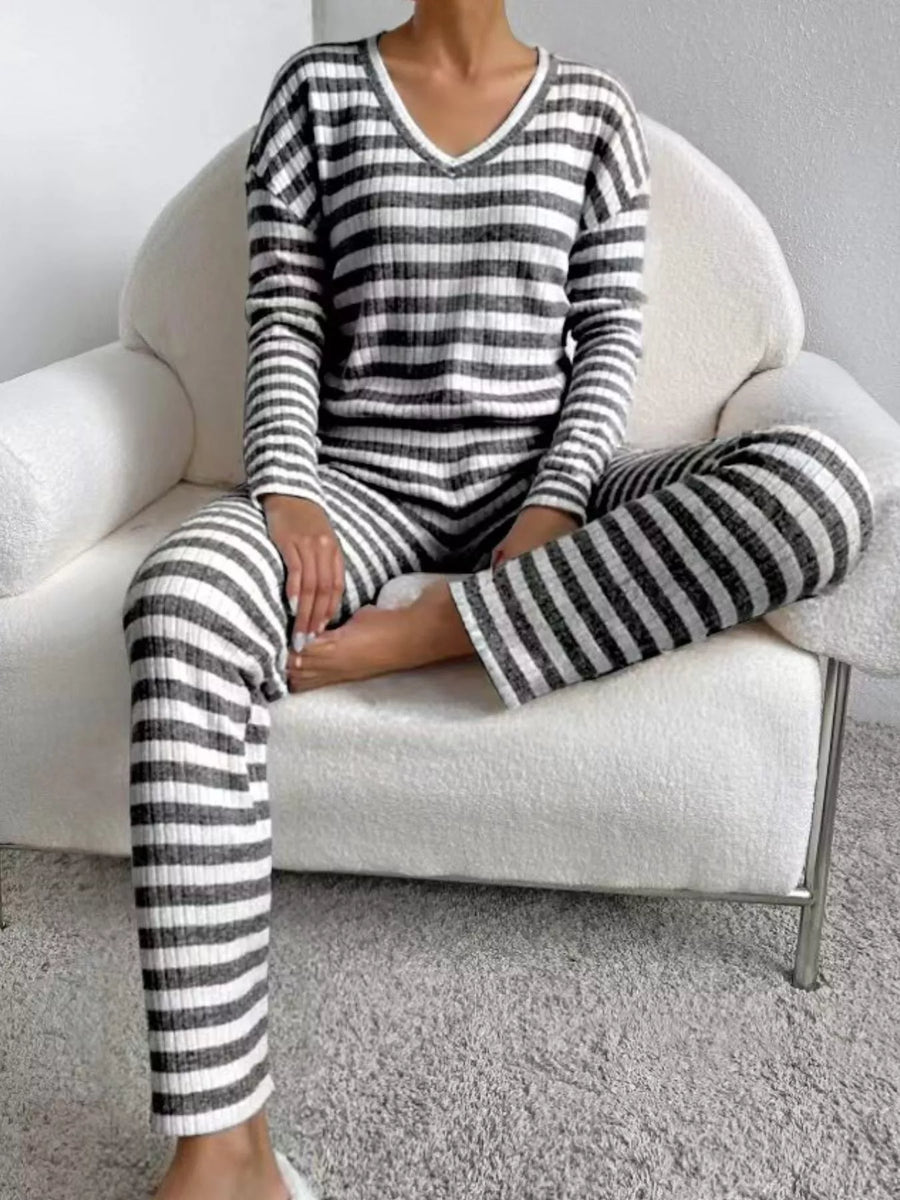 Person wearing black and white striped pajamas sitting on a white chair.