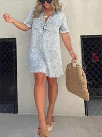 Woman wearing a light blue denim dress holding a woven bag against a plain background
