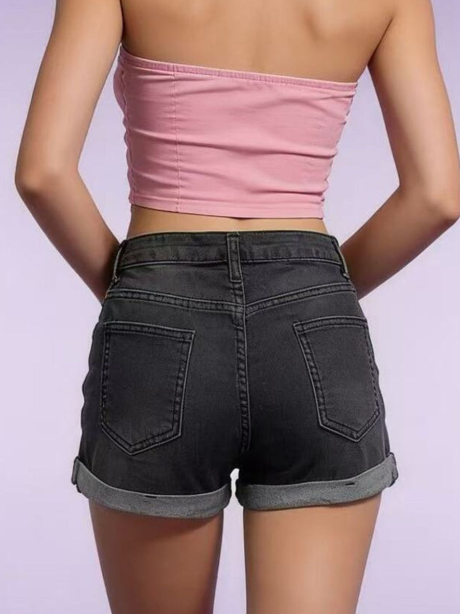 Person wearing a pink tube top and black shorts on a light purple background
