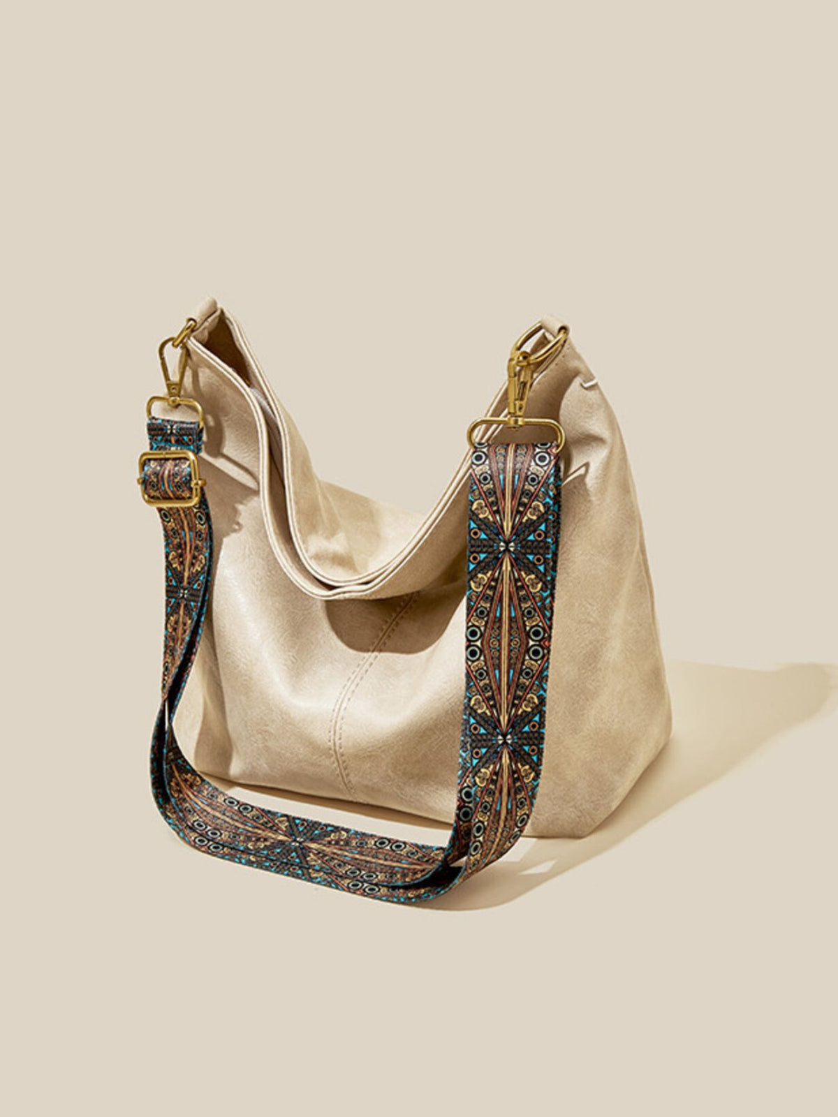 Beige handbag with an ornate strap on a beige background