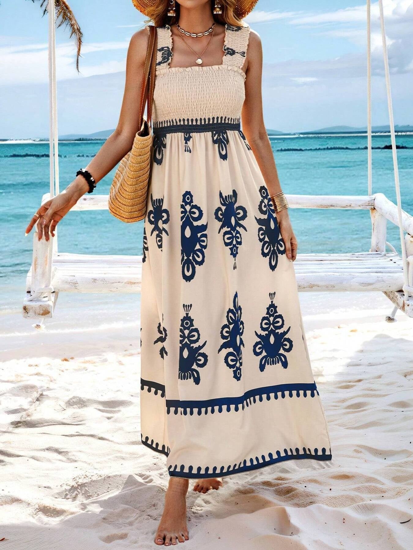 Woman in a long dress with blue patterns standing on a beach.