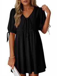 Black dress with puff sleeves worn by a model on a white background