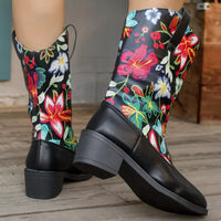Black rain boots with colorful floral embroidery on a wooden floor.