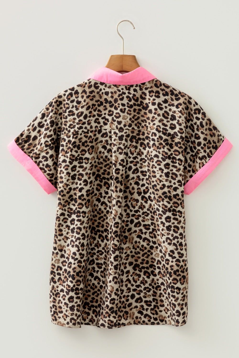 Leopard print dress with pink trim on a hanger against a white background