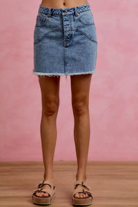 Denim skirt worn by a person on a pink background
