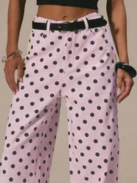 Pink polka dot pants worn by a person on a plain background