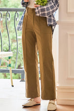Person wearing brown pants and a plaid shirt on a balcony.