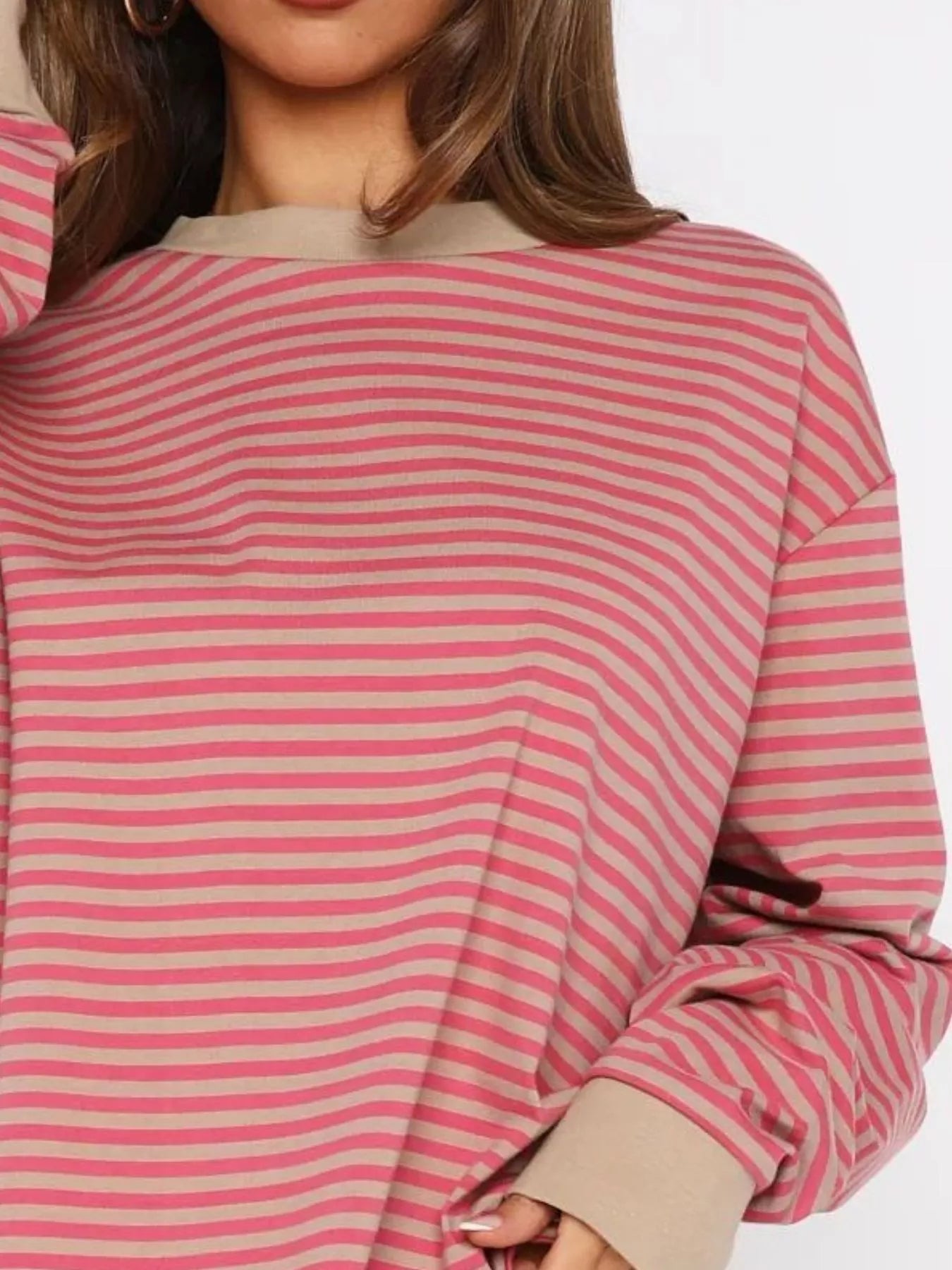 Close-up of a person wearing a pink and beige striped sweater with a neutral background