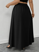 Person wearing a black long skirt against a plain background