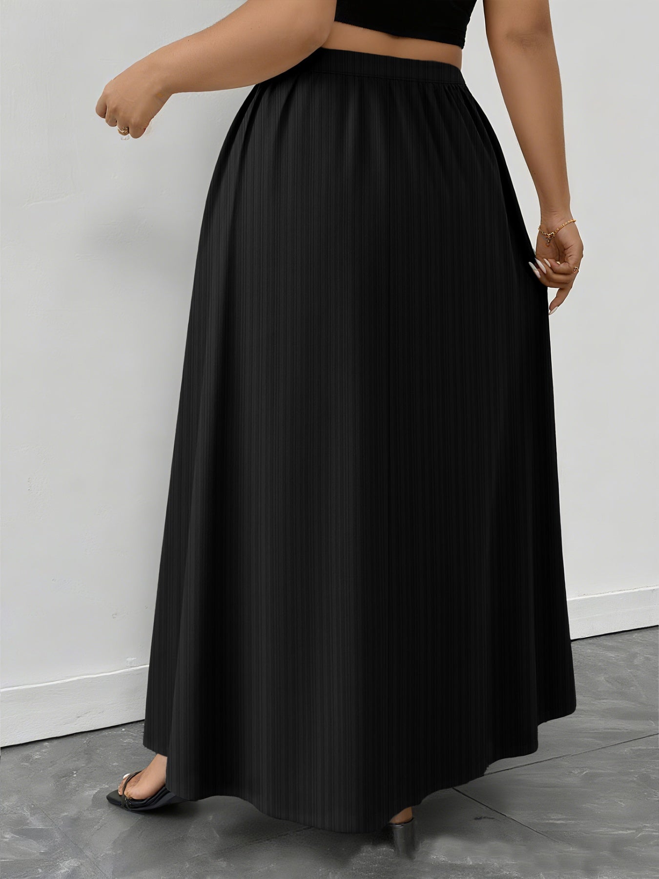 Person wearing a black long skirt against a plain background