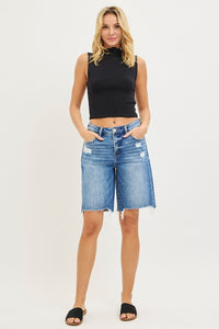 Woman wearing a black sleeveless top and denim shorts on a white background