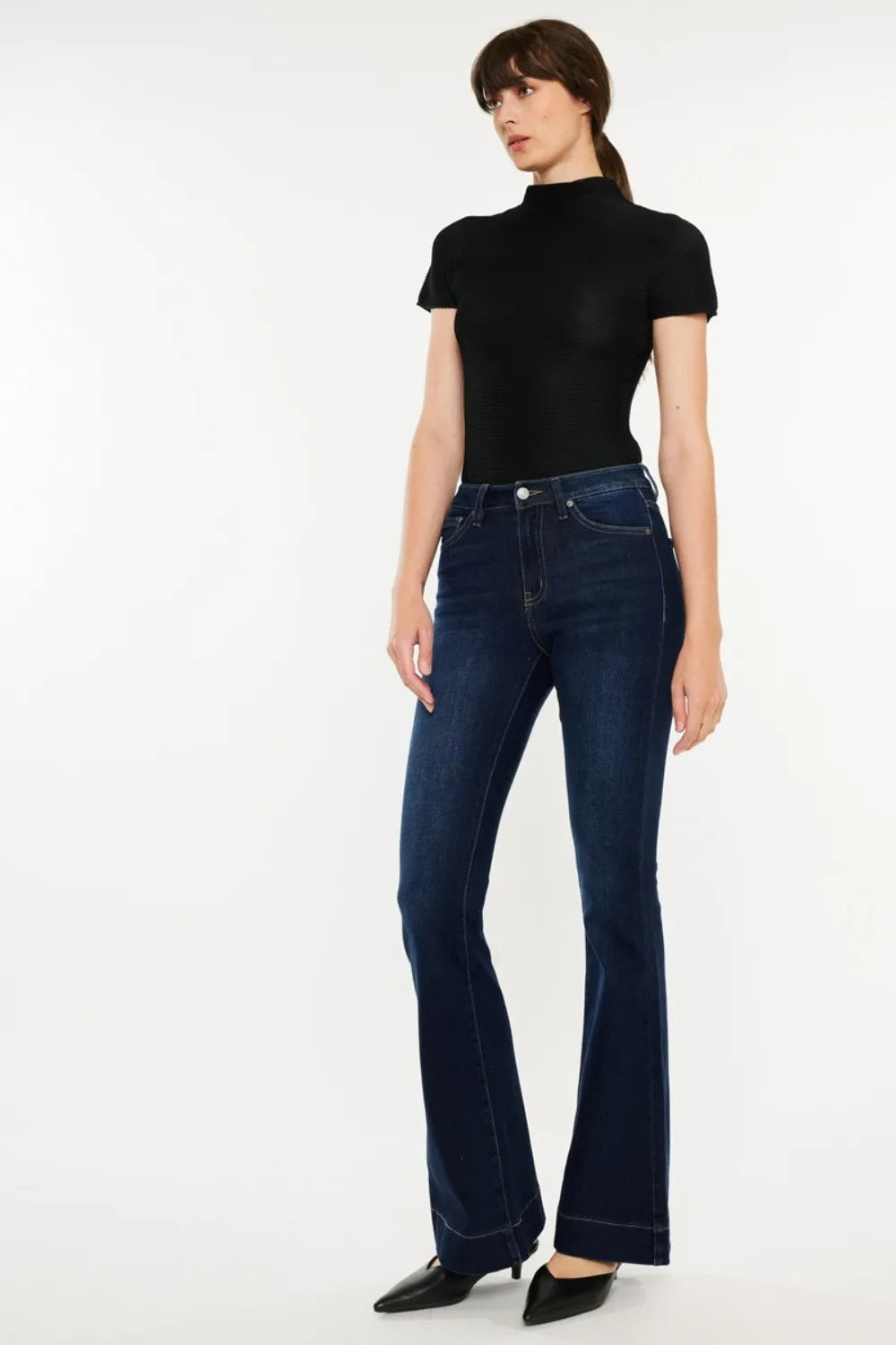 Woman wearing dark blue jeans and a black top on a white background