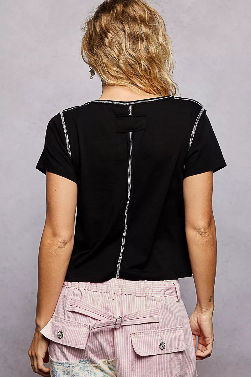 Person wearing a black top with white accents and pink pants on a gray background