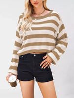 Person wearing a striped sweater and black shorts against a plain background
