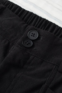 Close-up of black pants with button details on a white background