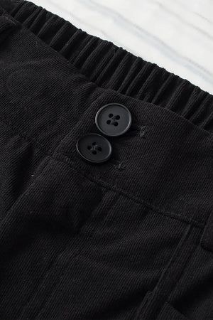 Close-up of black pants with button details on a white background