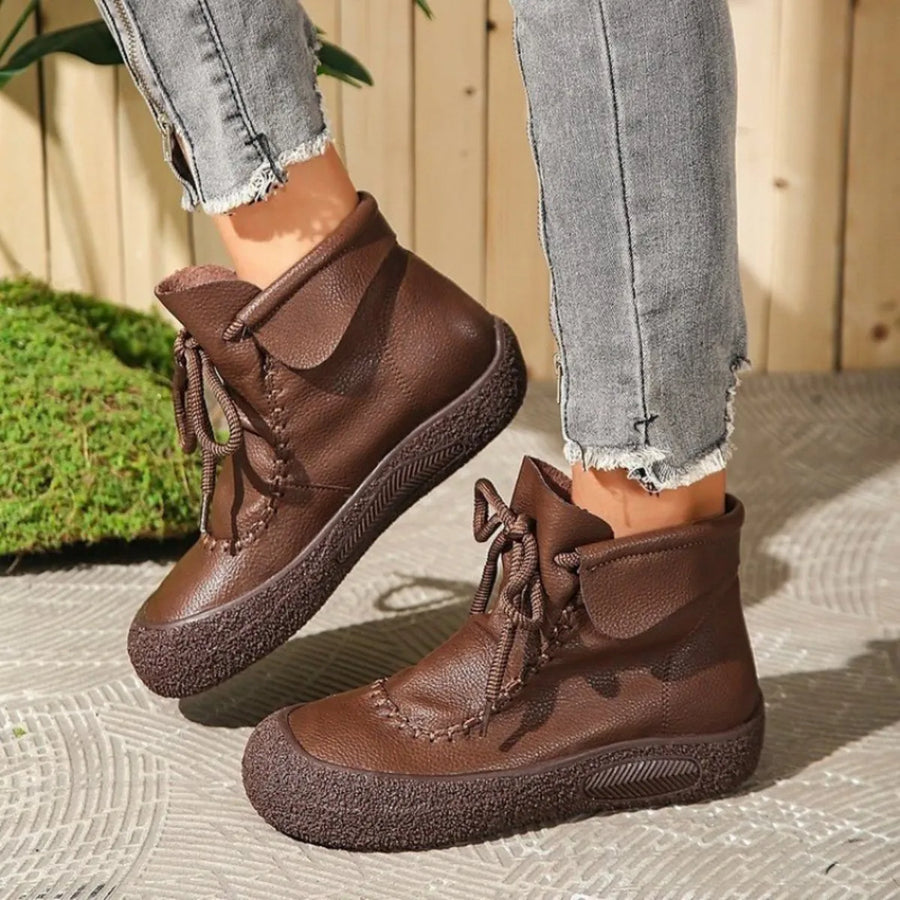 Brown boots worn with light gray jeans on a textured surface.