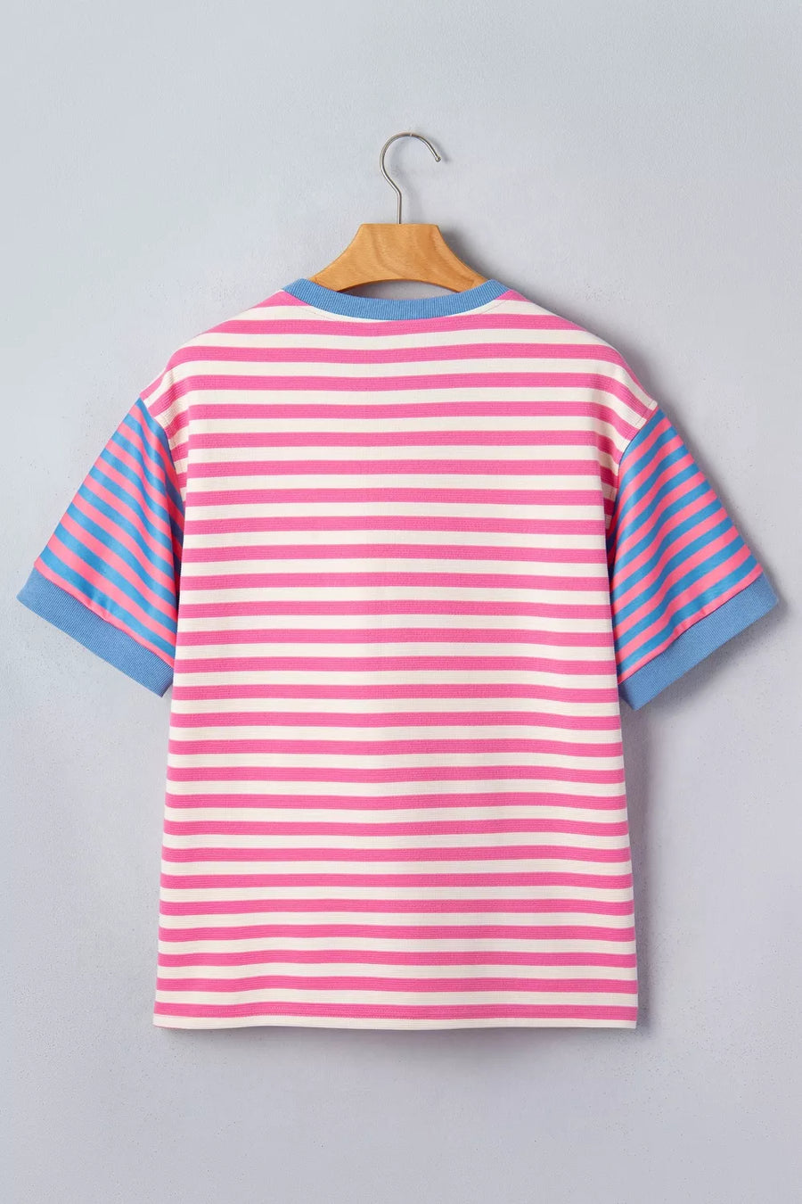 Pink and blue striped shirt on a hanger against a gray background