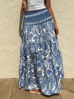 Person wearing a blue and white patterned skirt against a beige wall.
