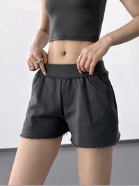 Person wearing black shorts and a crop top on a plain background