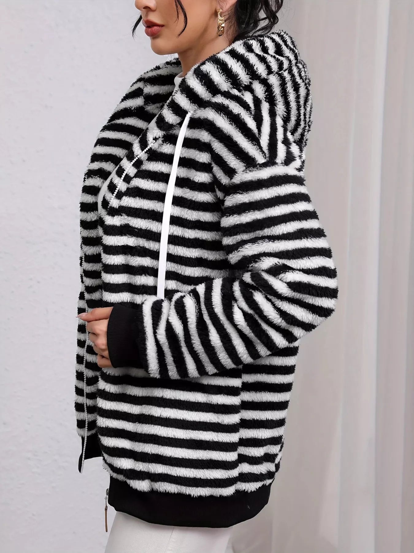 Black and white striped hoodie worn by a person on a plain background