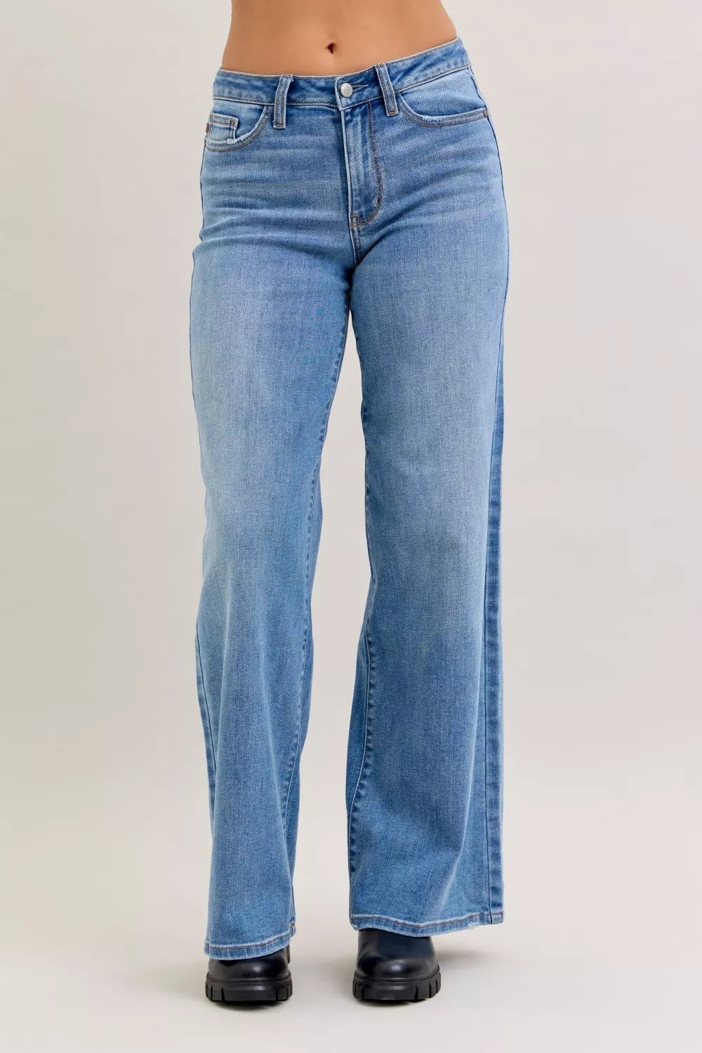 Blue jeans worn by a person on a plain background