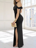 Woman in a black off-shoulder dress with a high slit, holding a gold clutch, in a bright room.