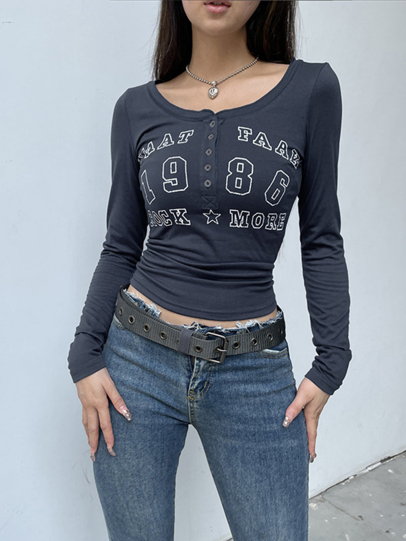 Person wearing a dark long-sleeve shirt with text and jeans against a light gray background