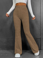 Person wearing brown ribbed pants and white sneakers against a gray background