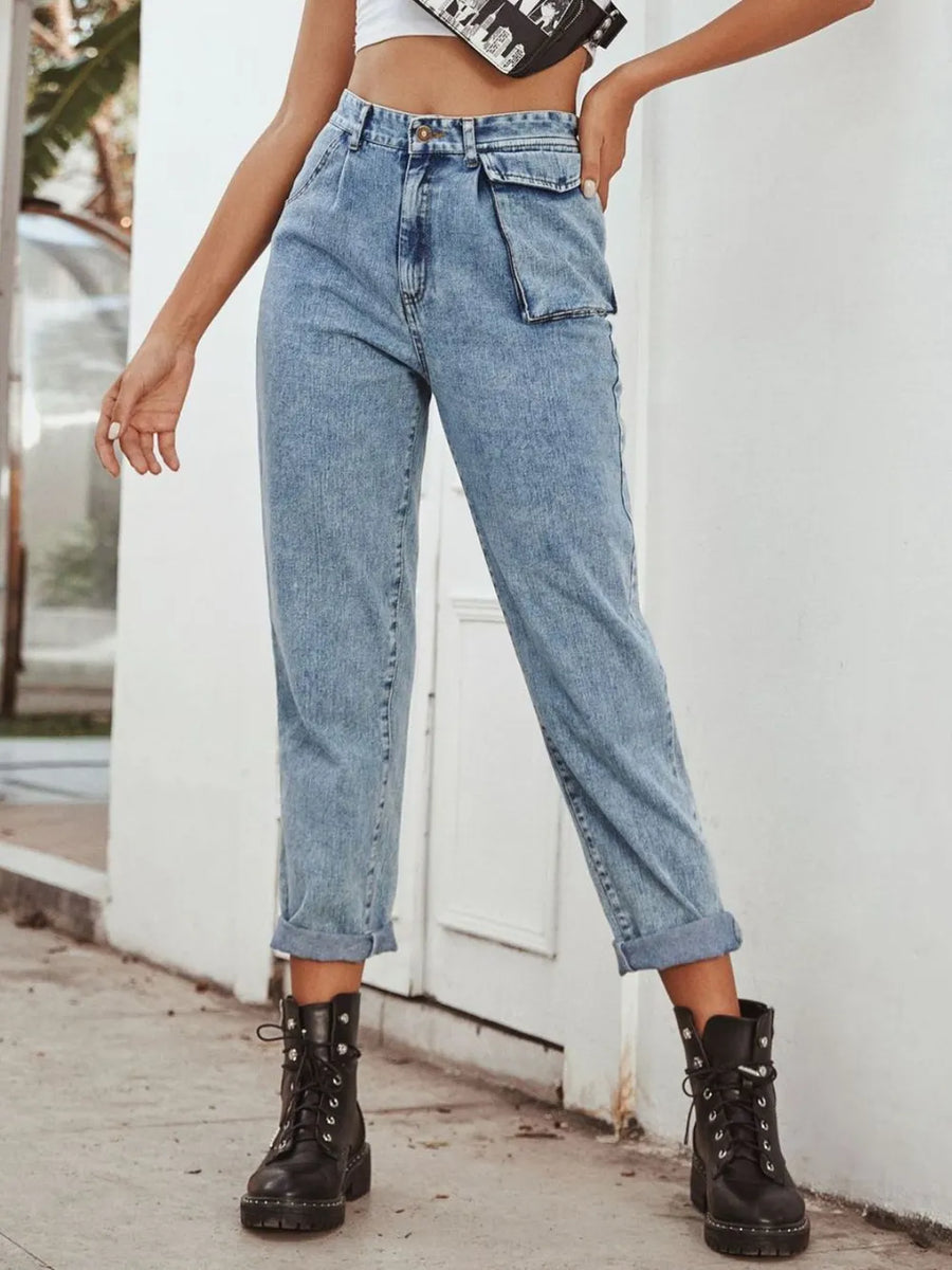 Person wearing high-waisted blue jeans and black boots on a white background