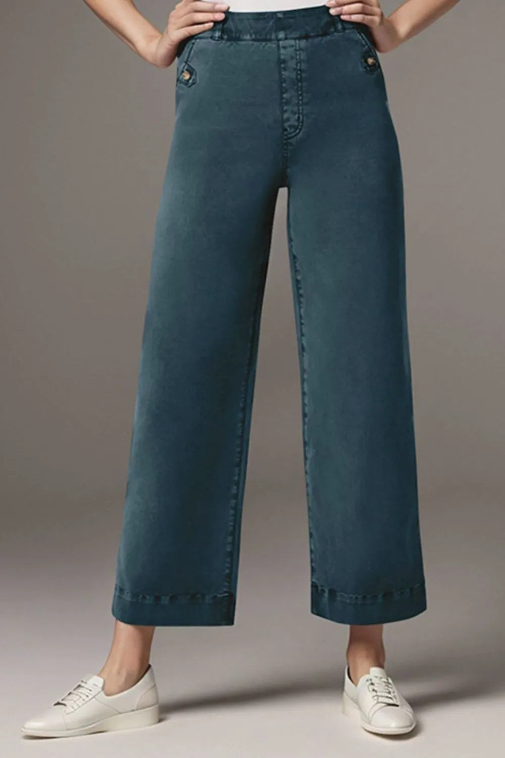 Teal wide-leg jeans worn by a person on a gray background