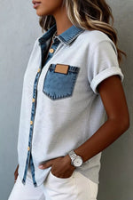 Person wearing a light gray shirt with denim accents against a neutral background
