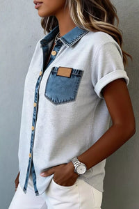 Person wearing a light gray shirt with denim accents against a neutral background