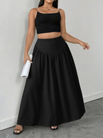 Woman wearing a black crop top and long skirt against a gray background