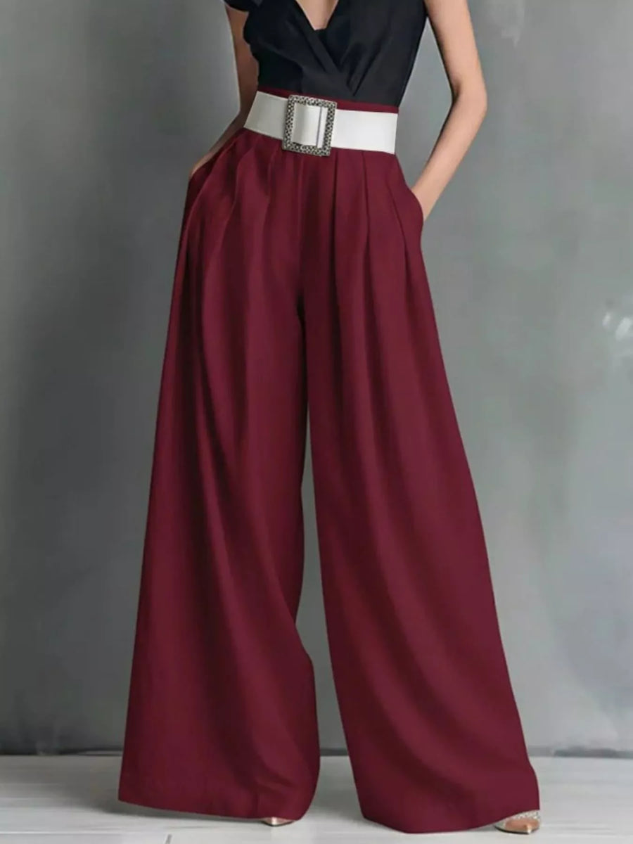 Maroon wide-leg pants with a black top and white belt on a gray background